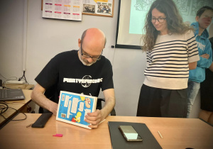 Autor wpisuje dedykacje do książki Zrób sobie komiks