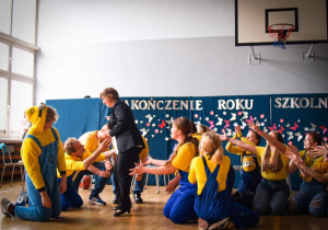 Minionki klęczą na podłodze a pani dyrektor Katarzyna Mielech wciela się w rolę Lucy Wild