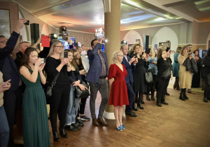Uczniowie klas czwartych tańczą poloneza w sali balowej.